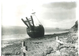 A wooden ship with three prongs on the bow sitting on the foreshore
